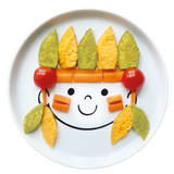 Assiette en porcelaine blanche avec une illustration de tête de bonhomme rigolos au centre. Elle est de la marque Cibolo , indiqué sur l’oval du visage. L’assiette permet de créer des repas rigolos en animant le personnage. Elle est composée de plusieurs purée avec des morceaux de carottes et des tomates cerise, elle représente un indien