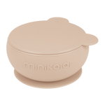 Bol en silicone de couleur beige avec un couvercle en forme de tête d'ours, sur le bol il y a l'inscription de la marque Minikoioi. Le bol est posé sur un fond transparant