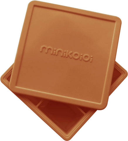 Moule multiportions en silicone de couelur marron avec un couvercle. Sur le couvercle il y ala marque qui est gravée : Minikoioi