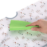 Gros plan sur la main d'une personne qui nettoie un bavoir en tissu pour enfant, à l'aide d'un chiffon vert