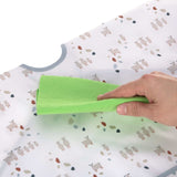 Gros plan sur la main d'une personne qui nettoie un bavoir en tissu pour enfant, à l'aide d'un chiffon vert