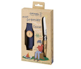 Photo sur fond blanc d'un coffret de couteau pour enfant de la marque Opinel contenant un couteau de poche à lame arrondi et son étuis de couleur bleu avec fermoir en cuir avec le logo Opinel. Sur la pochette du coffret est déssiné un jeune garçon autour d'un feu de camp qui taille un morceau de bois avec un couteau