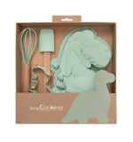 Coffret d'ustensiles de cuisines pour enfant de couleur vert pastel, présenté dans un coffret en kraft de la marque Scrap cooking. Les ustensiles sont en forme de dinosaure, il y a un un moule en silicone, un découpoir et un fouet et une spatule
