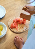 main d'enfant qui coupe des morceaux de pastèque à l'aide d'un coupe legumes en bois gravé de la marque Skagfa