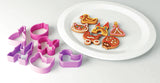 Assiette blanche avec des gâteaux dessus. Les gâteaux sont decorés avec des couleurs différentes. Sur le coté gauche de l'assiette, il y a les emportes-pièces qui ont permis de réaliser les gateaux. Les gateaux sont en forme de Princess, canard, chat, berceau, château et coccinelle