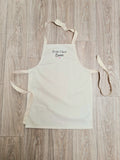 PHOTO D'UN TABLIER POUR ENFANT DE COULEUR BEIGE AVEC UNE INCRIPTION MANUSCRITE NOIRE AVEC PETIT CHEF EWENN ET EUN COEUR ROSE