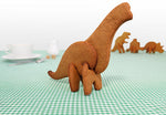 En avant plan Triceratops, dinosaure  en biscuits 3D et en arrière plan 3 autres dinosaures fait en biscuit. Les dinosaure sont sur une table dont la nape est en vichy vert