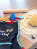 Table de cuisine avec tablier enfant, pate a sablé sur set et rouleau a pâtissier