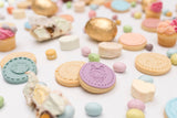 Zoom sur un biscuit recouvert de pâte à sucre mauve avec une illustration de petite fille avec des oreilles de lapin. Le biscuit est posé sur une table recouvert de biscuit et bonbon sur le thème de Pâque