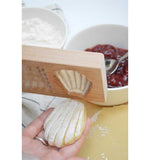 Gros plan sur une madeleine qui se demoule d'un moule à empreinte en bois. Le gâteau est en forme de madeleine