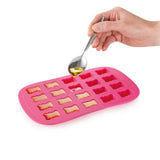 Moule à bonbon en forme de petits ourson et de couelur rose. Une main est entrain de remplir le moule à l'aide d'une petite cuillère