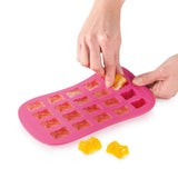 Moule à bon bon de couleurs rose et e en forme de petits oursons. Une main d'adulte est entrain de démouler les bonbons, dont 2 sont posés devant le moule.