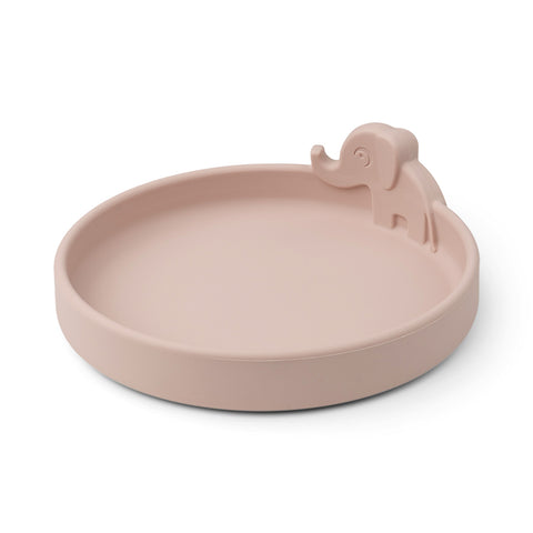 Peekaboo Assiette en silicone de couleur rose clair avec des rebords arrondies et un elephant en relief sur le rebord. La photo est prise sur un fond blanc