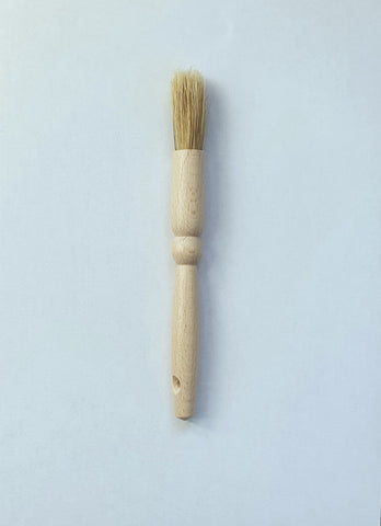 Photo d'un pinceau de cuisine avec un manche en bois et des poils en soie. Le pinceau est posé sur un fond blanc