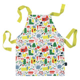 Photo d'un tablier sur fond blanc. Le tablier a des hanses de couleurs vertes, sur l'ensemble du tablier est illustrée des motifs sur le thème de la campgane : ferme, brouette, animaux, bottes, fruits et légumes