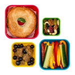 Photo prise en hauteur de l'intérieur de 4 boîtes à goûter de 4 tailles différentes, elles contiennent chacune un aliments pour composé un repas entier : sandwich + Légumes coupés en lamelle + fraises + fruits secs