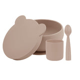 Coffret de vaisselle en silicone de couleur beige. il y a un bol avec son couvercle en forme de tête d'ours, un gobelet et une petite cuillère