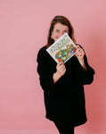 Photo de Manon Brzostek, qui tient entre ses mains son livre intitulé Croc Marelle