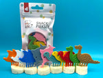 Ensemble de 10 piques alimentaires pour enfants. De formes et couleurs différentes. Ils sont piqués sur des morceaux de bananes, en arrière plan il y a l'emballage des pics