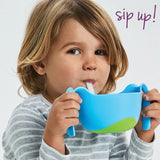 Jeune enfant qui boit grace à un bol de couleur bleu avec 2 poignées et une paille amovible