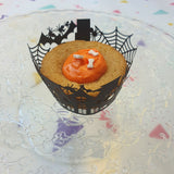 Cupckakes d'halloween posés sur un plateaux. Ils sont décorés avec un glaçage de couleurs oranges et des décors en sucre avec des yeux, tête de mort et os d'halloween