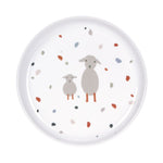 Assiette pour enfant en porcelaine posée sur un fond blanc. L'assiette est blanche avec des illustration de 2 moutons sur le milieu et des petits point de différentes couleurs. L'assiette est équipée d'un joint en silicone de couleur terra cota, comme les illustrations