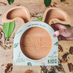 Assiette en bois pour enfant en forme de tête d'ours, elle possède 3 compartiments. L'assiette est tenu dans les main d'un enfant