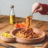 Photo d'une assiette pour enfant compartimenté avec des spaghettis à la bolognaise dans le compartiments principal ainsi que du mais et des carottes dans les autres. Une main d'enfant est entrain de se servir des pates avec une fourchette