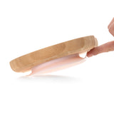 Dos d'une assiette en bambou en forme de souris. L'assiette a une ventouse en silicone de couleur rose. Sur le centre il y a des indication d'utilisation de gravé ainsi que le logo de la marque : Lässig. Il y a une main d'adulte qui soulève le joint en silicone.