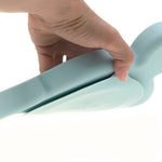 Gros plan sur la main d'un adulte retirant une assiette en silicone de couleur bleur. Il tient dans sa main une partie de la ventouse intégrée à l'assiette