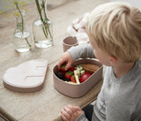 Photo d'un enfant assis à table entrain de manger des fraises disposées dans une boîte à goûter en forme d'elephant.