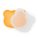 Bol pour enfant en forme de tête d'ours de couleur jaune avec un couvercle opaque blanc. Les 2 sont en silicone et ils sont photographiés sur un fond blanc