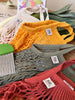Ensemble de 4 filets à provision de 4 couleurs différentes posés les uns sur les autres. Le 1er est de couleur rouge, le 2eme Kaki, le 3ème jaune et le dernier beige