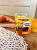 Photo d'un emballage en carton de couleur jaune d'une plante à planter. La plante s'appelle ma plante qui pétille. Elle est posée sur une table en bois avec des carottes en arrière plan