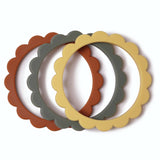 Ensemble de 3 bracelets en silicone, posés les uns devant les autres. ils sont en forme de fleurs et ont 3 couleurs différentes : sable, sauge et jaune