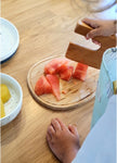 main d'enfant qui coupe des morceaux de pastèque à l'aide d'un coupe legumes en bois gravé de la marque Skagfa