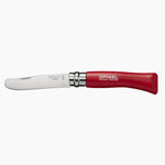 Couteau pour enfant pliable sur fond blanc. Le couteau à un manche en bois de couleur rouge avec la marque Opinel gravé dessus. La lame est arrondie et la marque et le logo Opinel est également gravée dessus