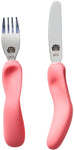  Une fourchette et un couteau aux manches ergonomiques de couleur rose, posé les un a coté des autres. Les couverts sont en inox avec la marque gravé sur le dessus, il s’agit de la marque Nana’s Manners représenté par une tête de mamie