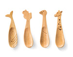 4 cuilères en bambou en forme de 4 animaux différents posées sur un fond blanc. Les cuillères pour enfant sont de formes : baleine, écureuil, oie et giraffe