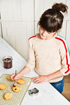 Photo d'une jeune fille qui décore des sablés posés sur une grille de cuisine