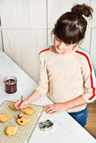 Photo d'une jeune fille qui décore des sablés posés sur une grille de cuisine