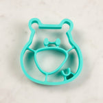 Petiit moule en silicone posé sur une table blanche, la moule est de couleur turquoise et il a la forme d'une tête d'ours