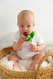 Photo d'un bébé qui est assi et tient dans sa bouche en jouet de dentition en forme de cerise