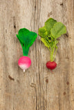 Photo d'un radis en caoutchouc déstiné a être un jouet posé à coter d'un vrai radis. Les 2 ressemble à l'identique. les 2 sont posés sur une planche en bois