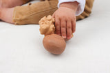 Anneau de dentition pour enfant en forme de noix avec et sans sa coque. La marque du jouet est gravé sur une noix, il s'agit d'Oli & Carol. Le jouet est en caoutchouc et ses couleurs sont trés proches de la réalité. Le jouet est tenu dans la main d'un bébé