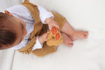 Anneau de dentition pour enfant en forme de cacahuète  avec et sans sa coque. Le jouet est en caoutchouc et ses couleurs sont trés proches de la réalité. Sur la photo le jouet est tenu dans les main d'un bébé