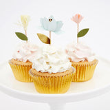 Photo de 3 cupcakes avec un glassage de couleur blanc, ils sont décorés avec des pics en forme de fleurs et caissettes dorées