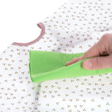 Gros plan sur la main d'une personne qui tient une lavette de couleur verte, la personne est entrain de nettoyer un tablier pour enfant