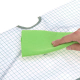 Gros plan sur la main d'un adulte qui tient une lavette verte dans la main et qui semble nettoyer un tissus blanc avec des rayures vertes
