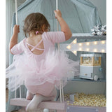 Photo d'une jeune fille habillée avec un tutu rose en danseuse, qui monte dur un trapèze. En arrière plan il y a une machine à pop corne avec des pop corn un peu partout